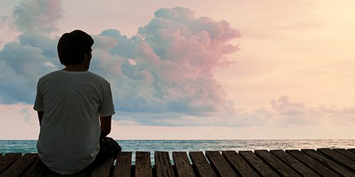 Man sitting on pier watching the sun set
