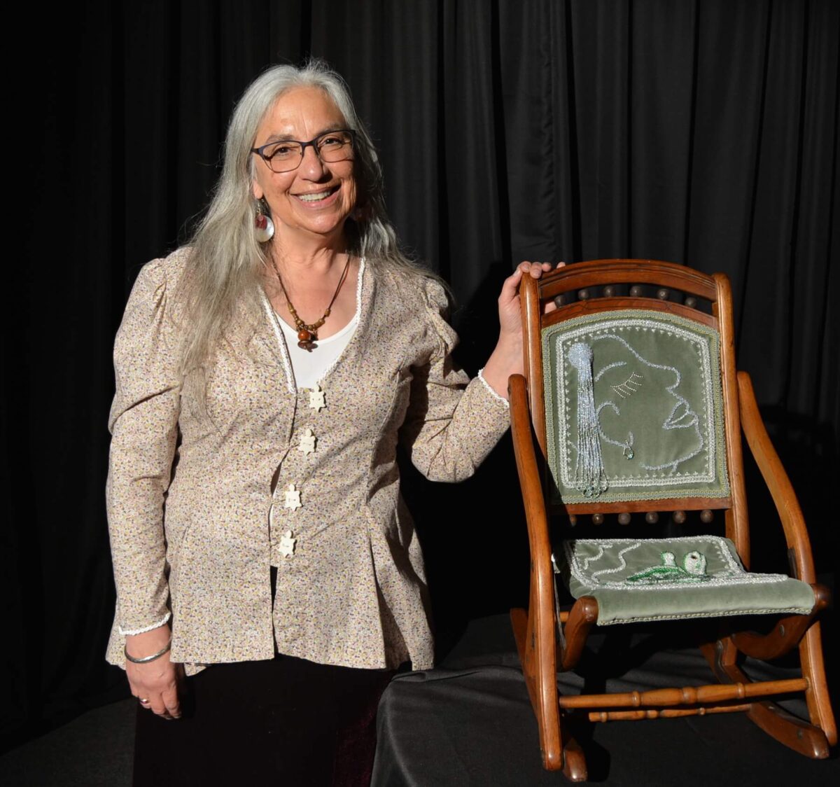 Artist Karen Ann Hoffman standing next to a chair she embroidered with beads