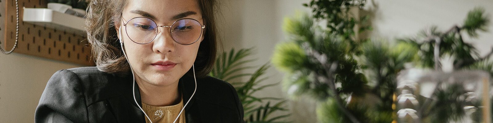Woman wearing glasses and headphones working in an office