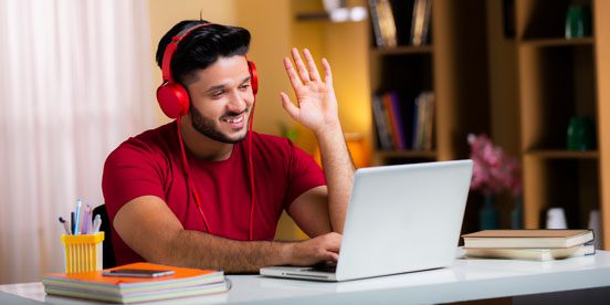 Man wearing headphones waves at laptop