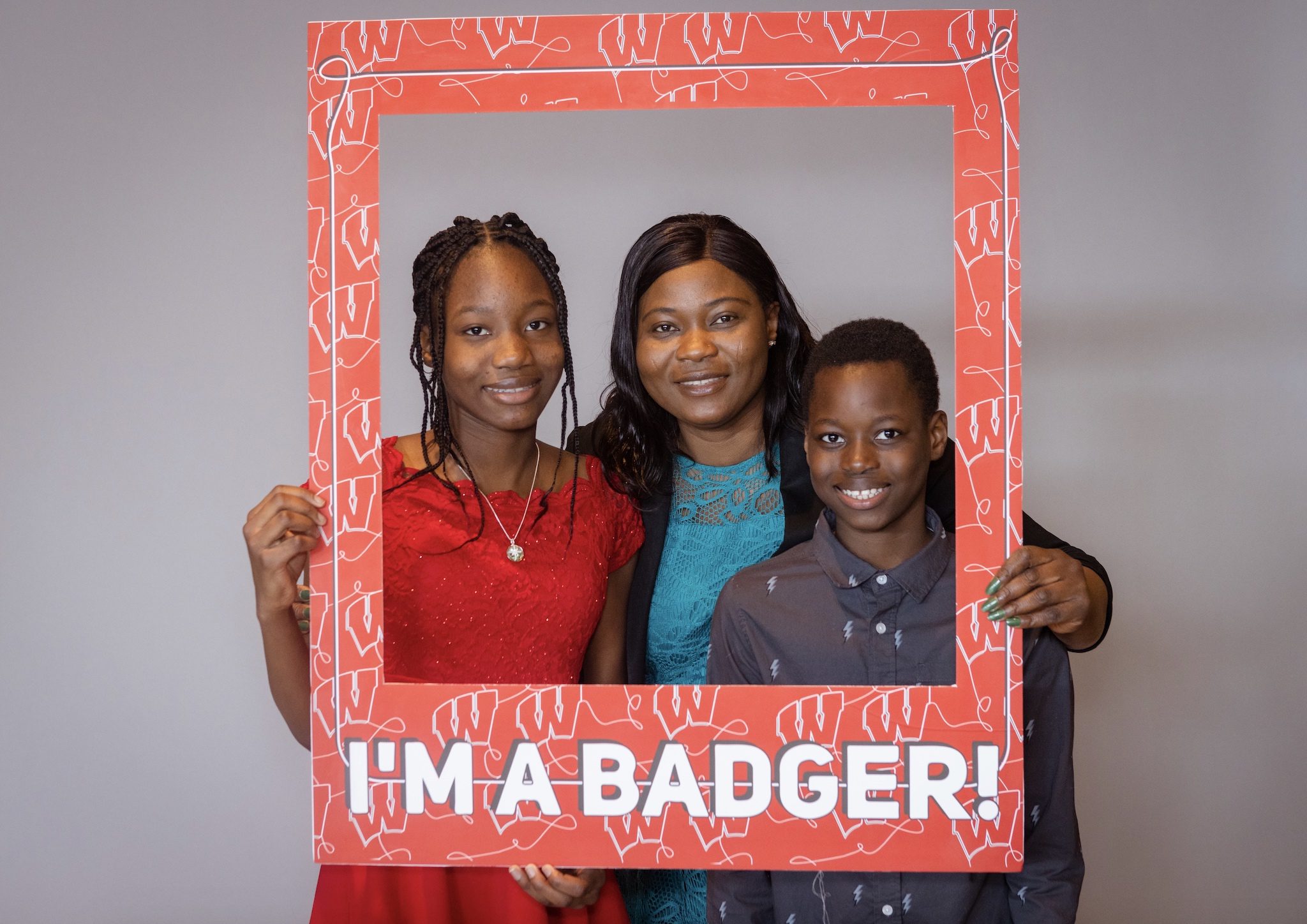 A woman and her two kids standing behind a sign that says "I'm A Badger."