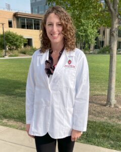 Christine Fifarek in her white lab coat, standing outside and smiling