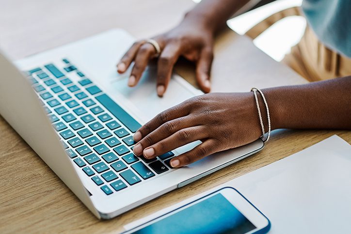 Hands wearing bracelets on keyboard, person doing a job search online