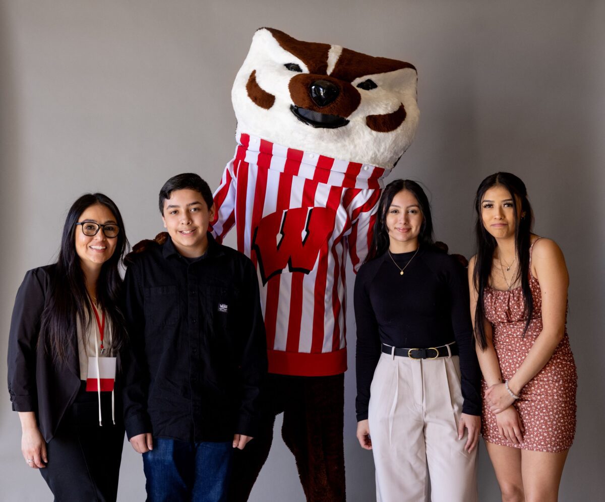 Dora Aranda with guests, standing and smiling with Bucky Badger