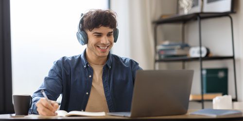 Smiling man wearing headphones working on laptop