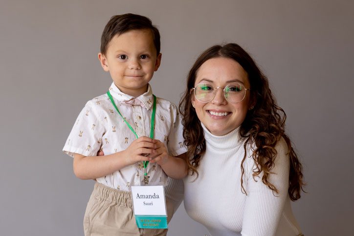 Amanda Sauri kneels next to her young son