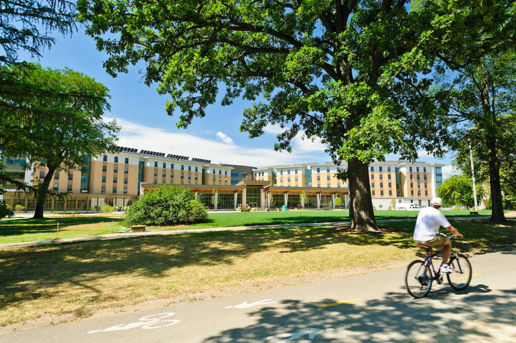 A man biking on the Lakeshore bike path past DeJope residence hall