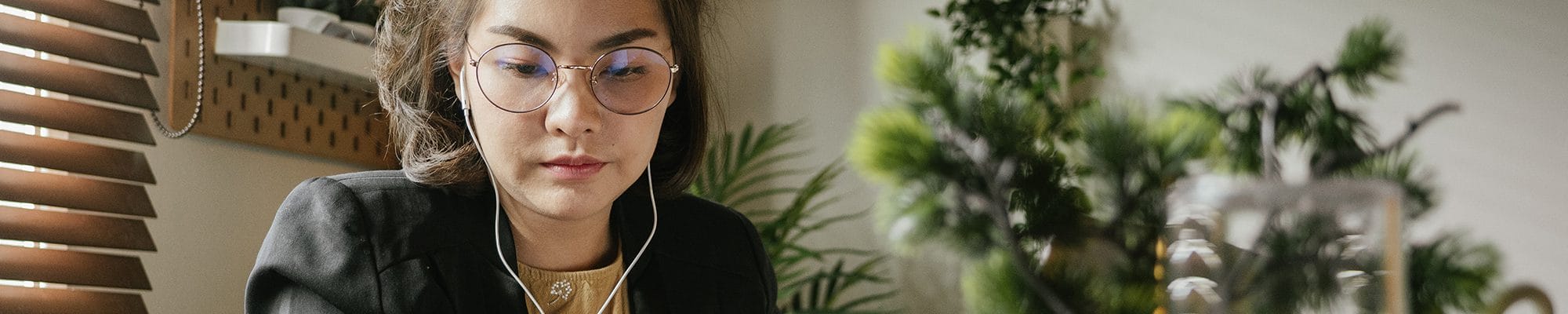 Woman wearing glasses and headphones working in an office