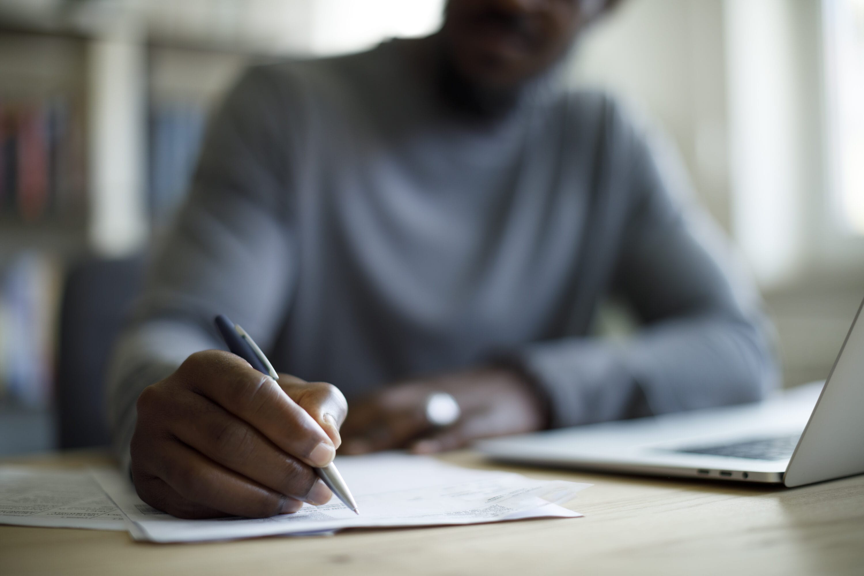 Person writing on a piece of paper, out of focus