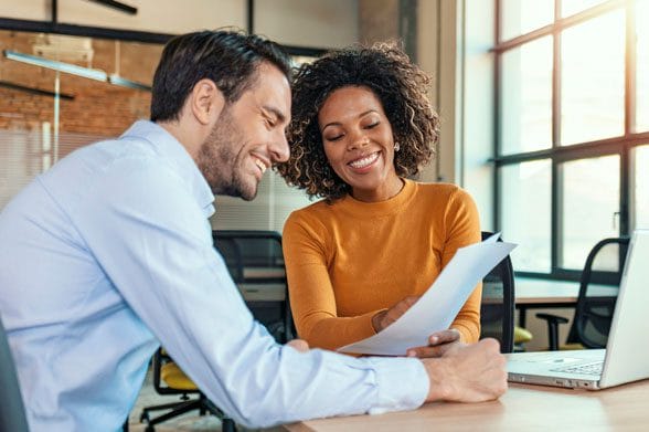 A happy looking supervisor has a meeting with her equally happy looking employee