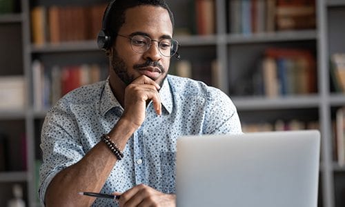 A man looks thoughtfully at his computer