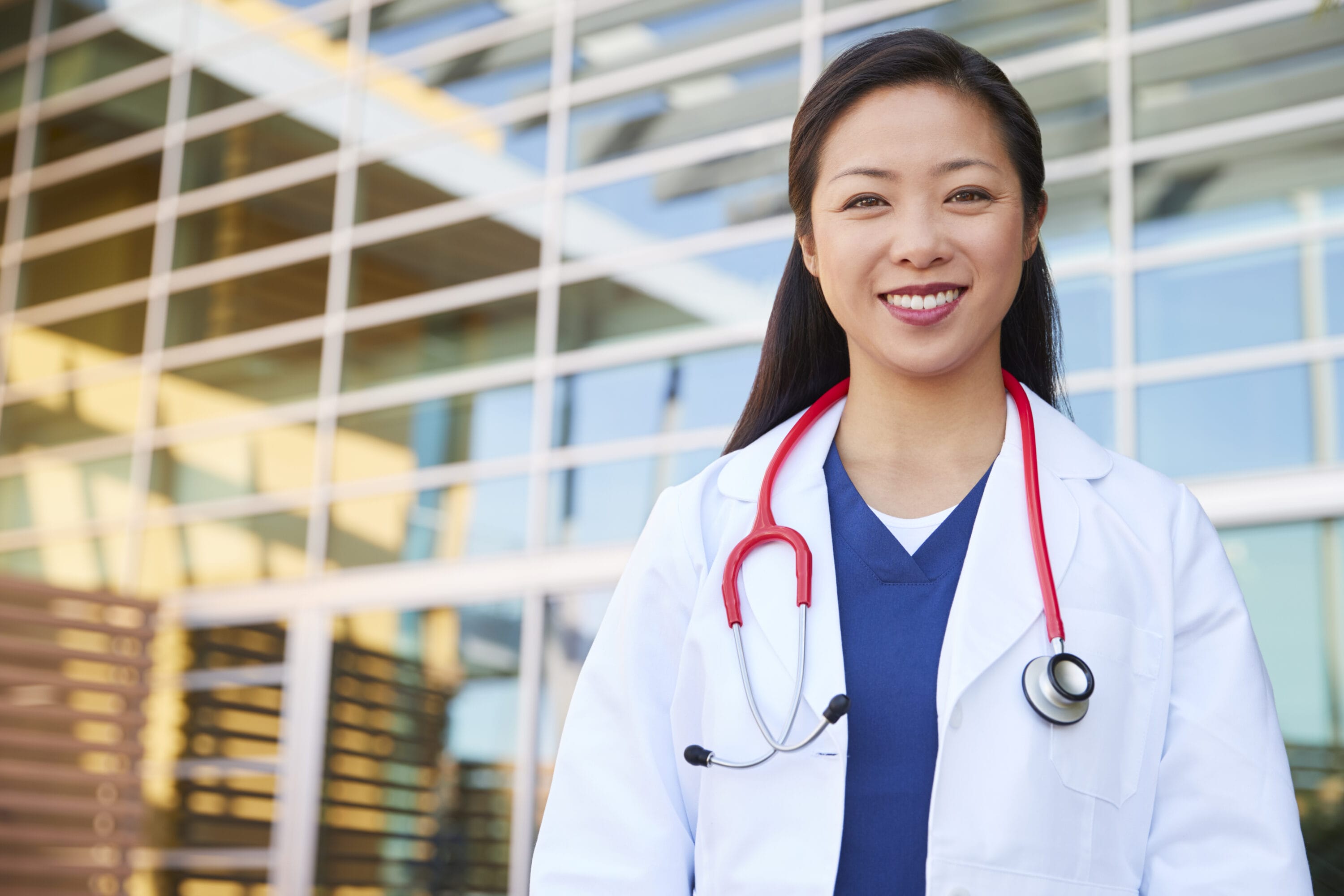 A woman in a white lab coat smiling at the camera.