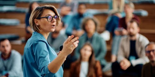 A woman giving a presentation to a group of students.